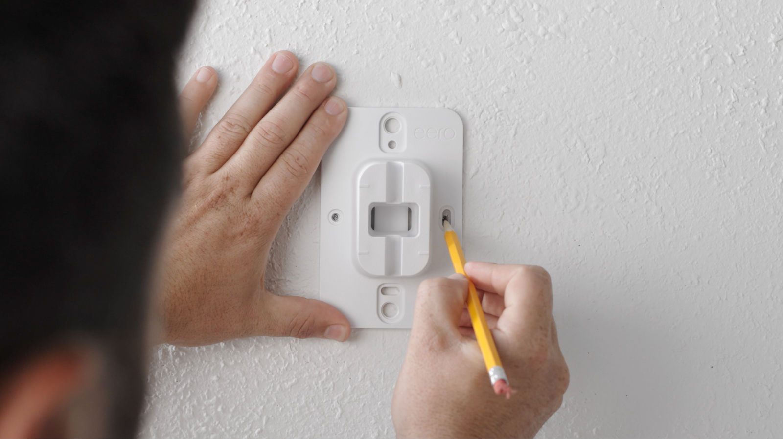 using mounting bracket to mark screw placement with pencil on wall