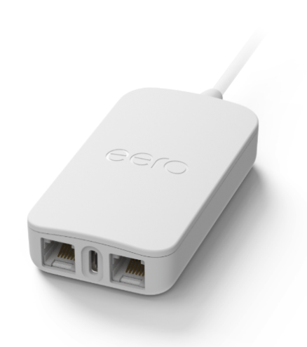 Adaptador telefónico eero con dos puertos Ethernet y un puerto USB-C en el panel frontal, con un cable de alimentación blanco conectado en la parte trasera.